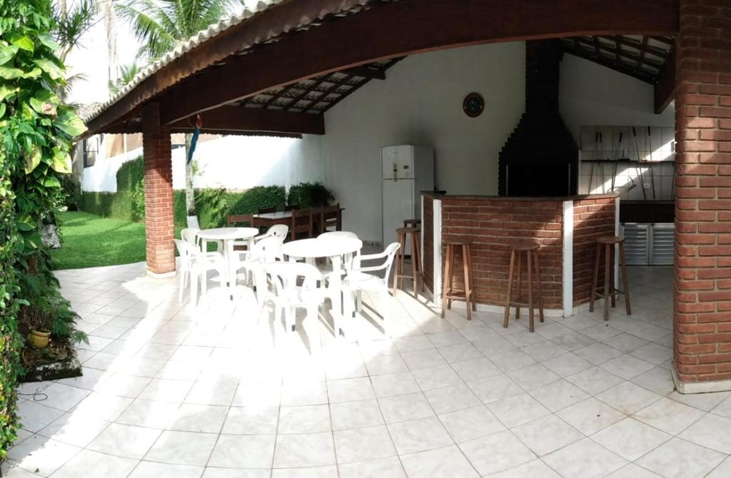 eine Terrasse mit weißen Tischen und Stühlen unter einem Pavillon in der Unterkunft Guaruja - Enseada in Guarujá
