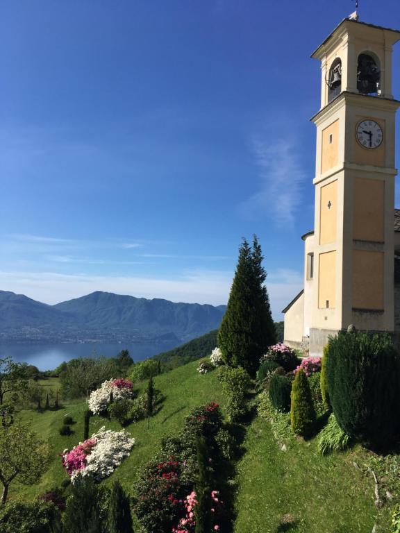 una torre del reloj en la cima de una colina con flores en Casa al Campanile, LeonardosHome, en Trarego