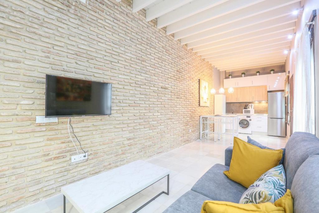 uma sala de estar com um sofá e uma parede de tijolos em Apartamento Alfarería em Sevilha