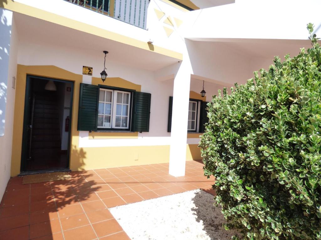 a house with a door and some bushes at Casa Margmar in Vila Nova de Milfontes