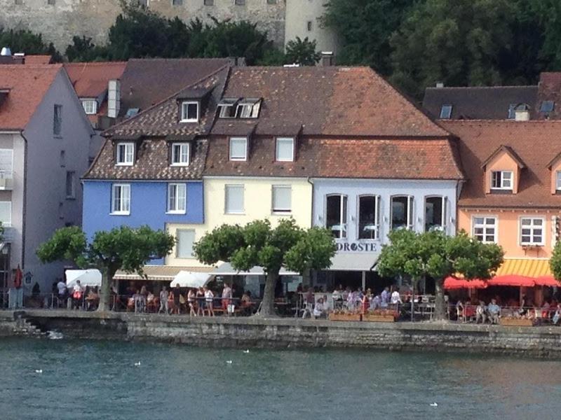 a group of people sitting outside a building next to the water at Hotel la Perla in Meersburg