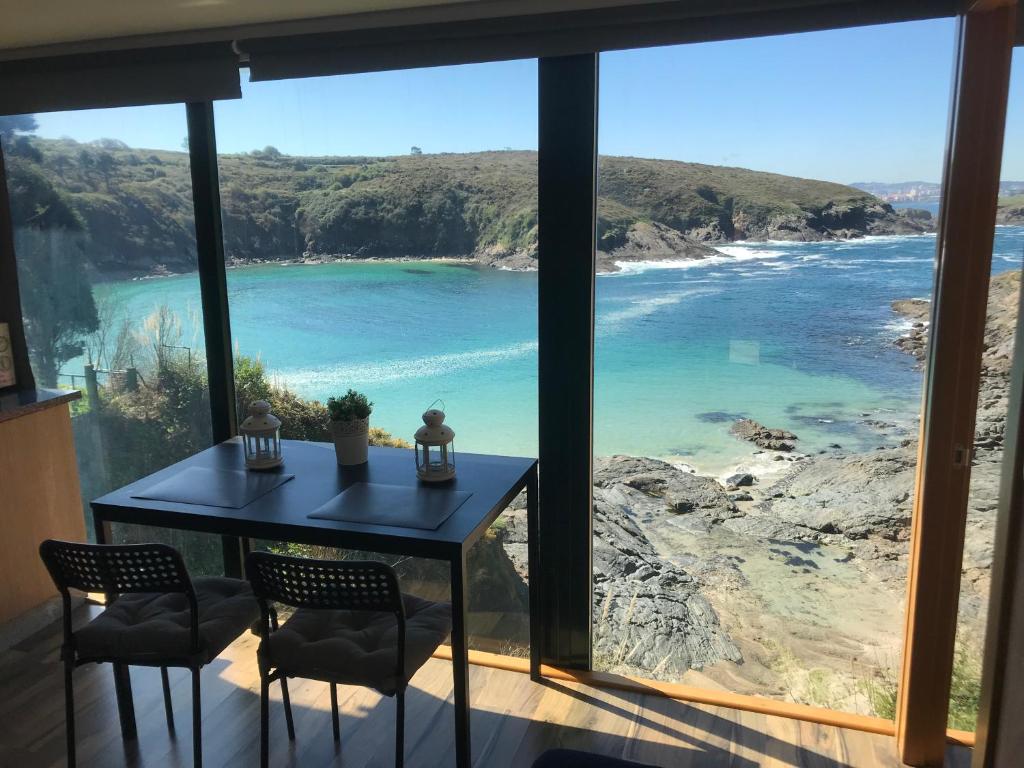 a table and chairs in a room with a view of the ocean at Apartamentos Canabal in A Coruña