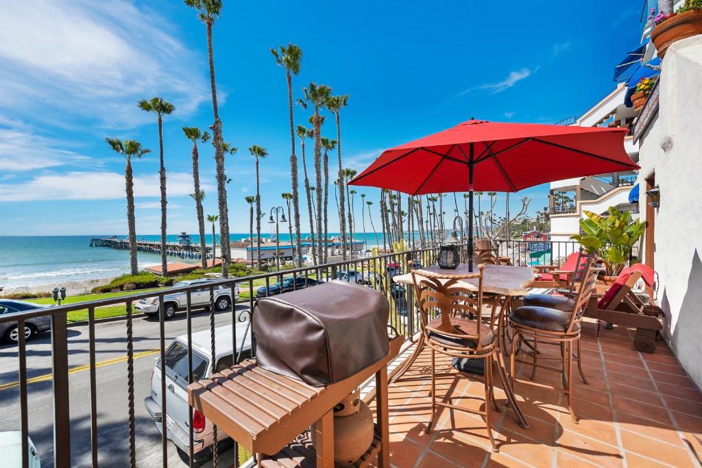 a patio with chairs and an umbrella and the beach at Oceanfront Hacienda in San Clemente