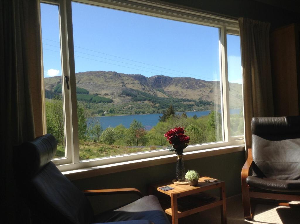 a window with a view of a lake and mountains at "An Comaraich - The Sanctuary" in Inverinate