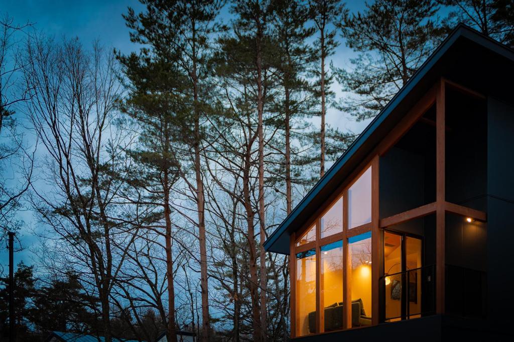 a house in the woods at night with trees at Black Crane Chalet by Hakuba White Fox Company in Hakuba