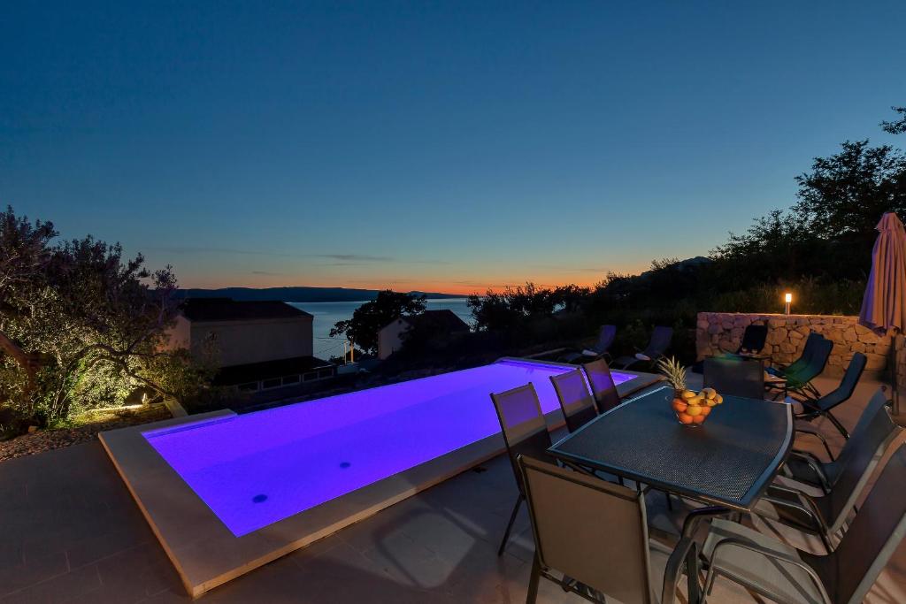 a patio with a table and a swimming pool at night at Villa NiMa in Brela