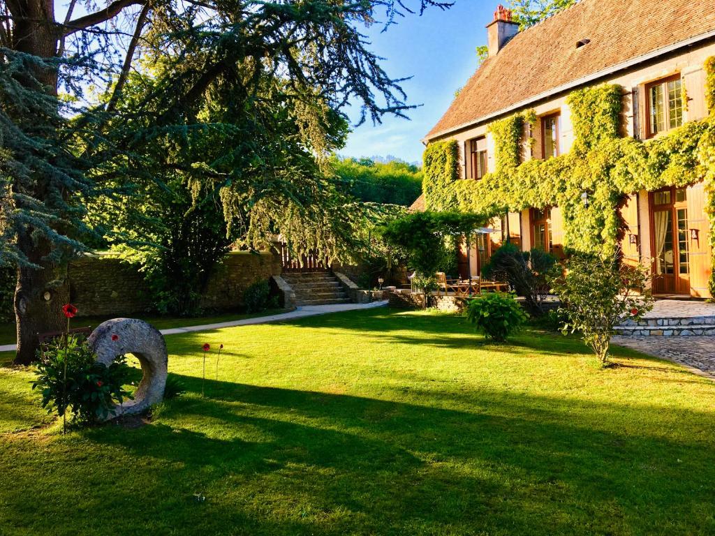 una casa con un jardín con una estatua en el patio en L'Orée du Mans, en Sillé-le-Philippe