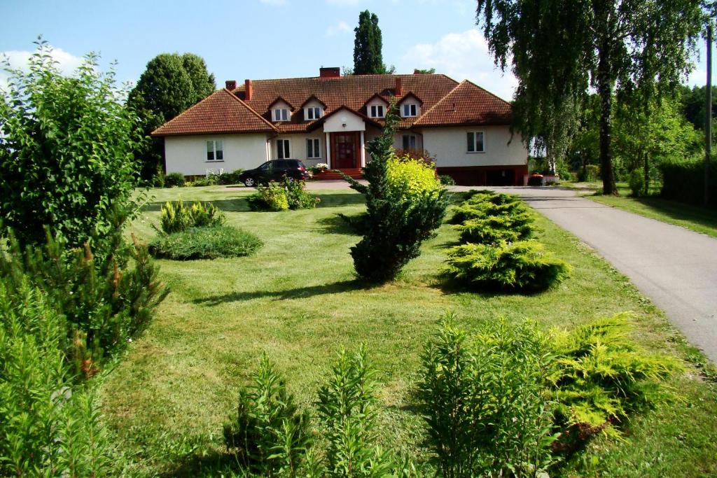 una casa con un patio con plantas delante en Pensjonat Dworek Baranówka, en Goniądz