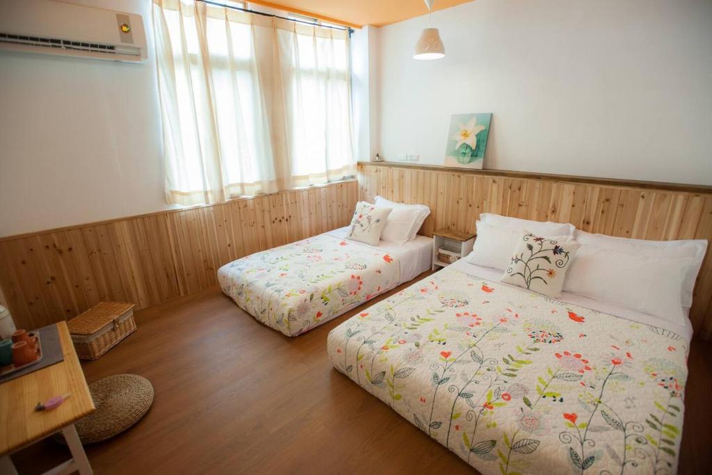 a bedroom with two beds and a desk and window at It's a Good Time Homestay in Guangfu