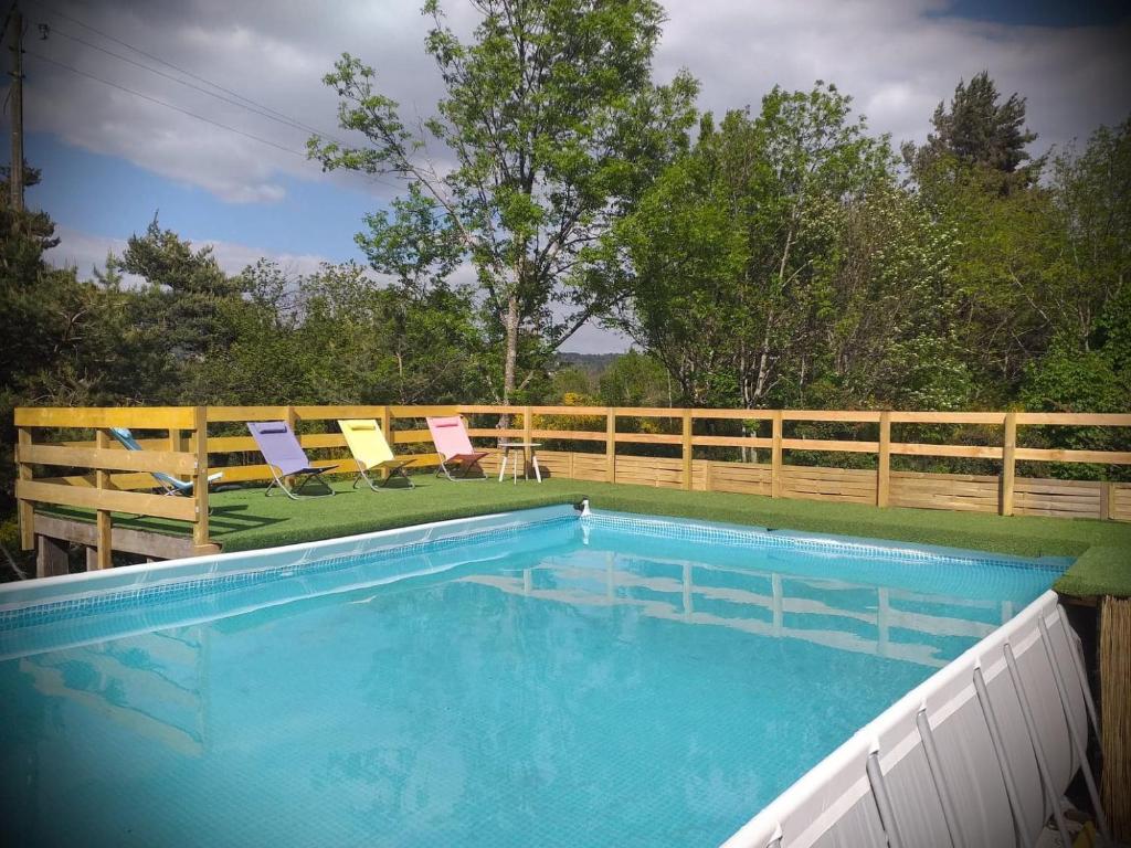 a swimming pool with two chairs and a fence at Un petit coin de paradis in Gluiras