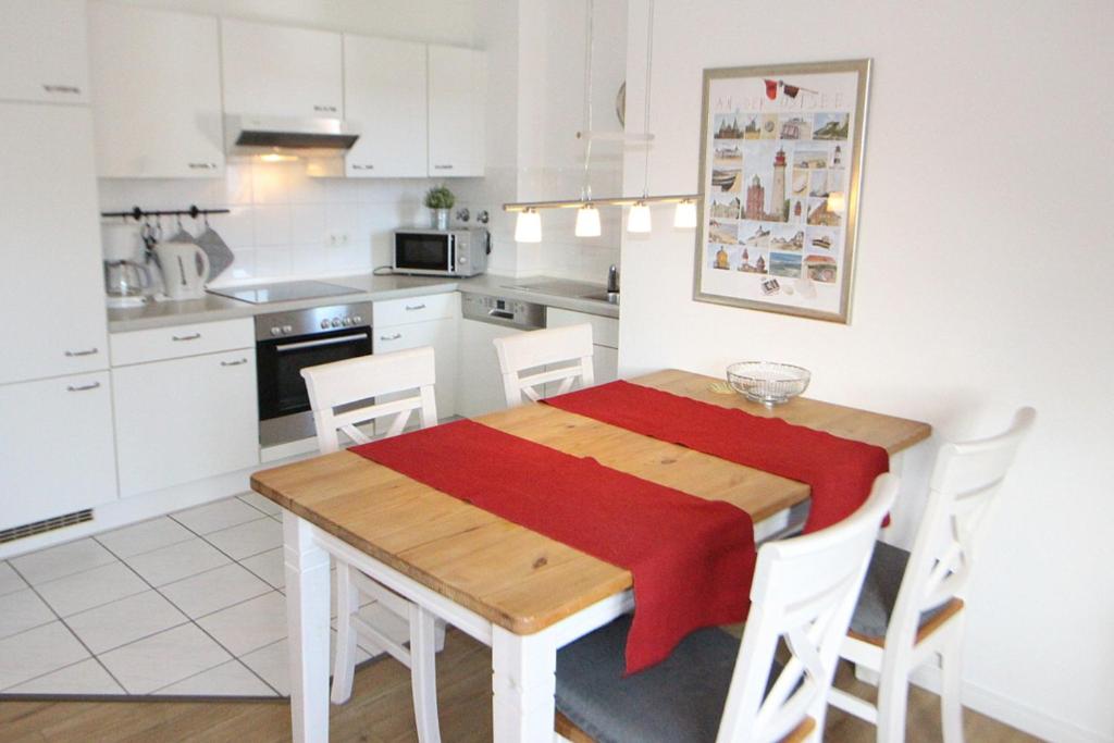 a kitchen with a wooden table with a red blanket on it at Apartmentvermittlung Mehr als Meer - Objekt 41 in Niendorf