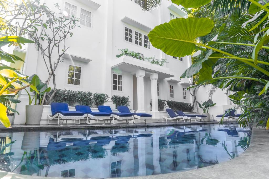 a hotel swimming pool with blue chairs and a building at Umalas Suites in Seminyak