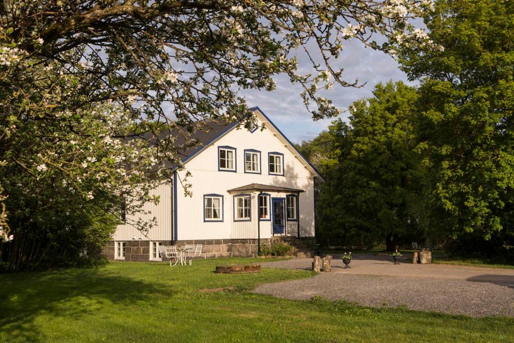 una casa blanca en un patio con árboles en Anna´s Bed & Kitchen en Varberg
