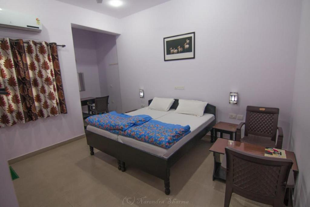 a bedroom with a bed and a table and a desk at Sanctuary Tourist Lodge in Bharatpur