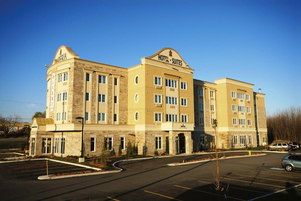 a large yellow building with a car parked in a parking lot at Imperia Hotel & Suites Saint-Eustache in Saint-Eustache