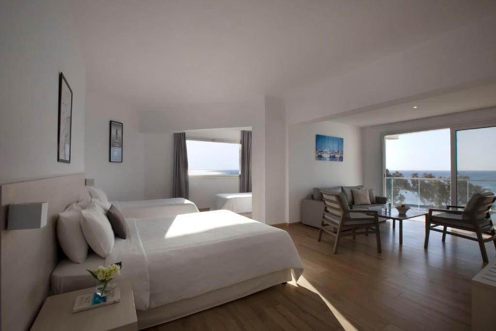 a bedroom with a white bed and a living room at Harmony Bay Hotel in Limassol