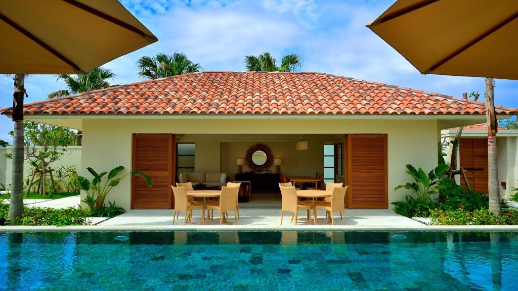 a house with a table and chairs next to a pool at The Uza Terrace Beach Club Villas in Yomitan