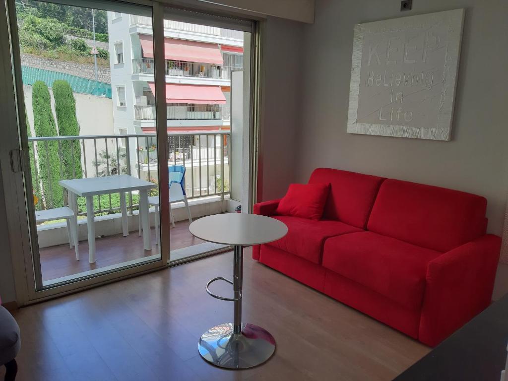 a living room with a red couch and a table at Studio Plage Les Sablettes in Menton