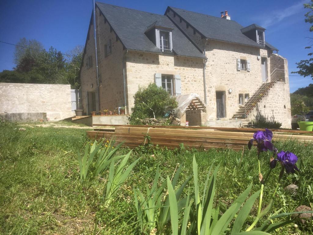 uma velha casa de pedra com flores roxas em frente em Le Dosne em Saint-Didier-sur-Arroux