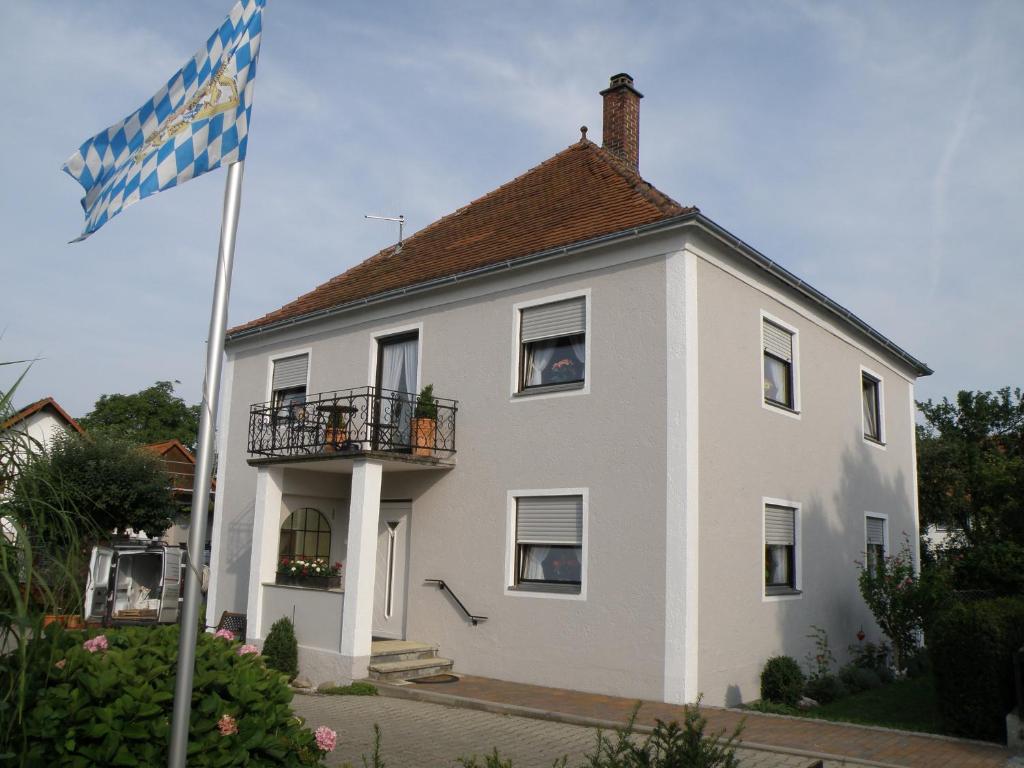 a white house with a flag in front of it at Zimmervermietung Ziegltrum in Wolfersdorf