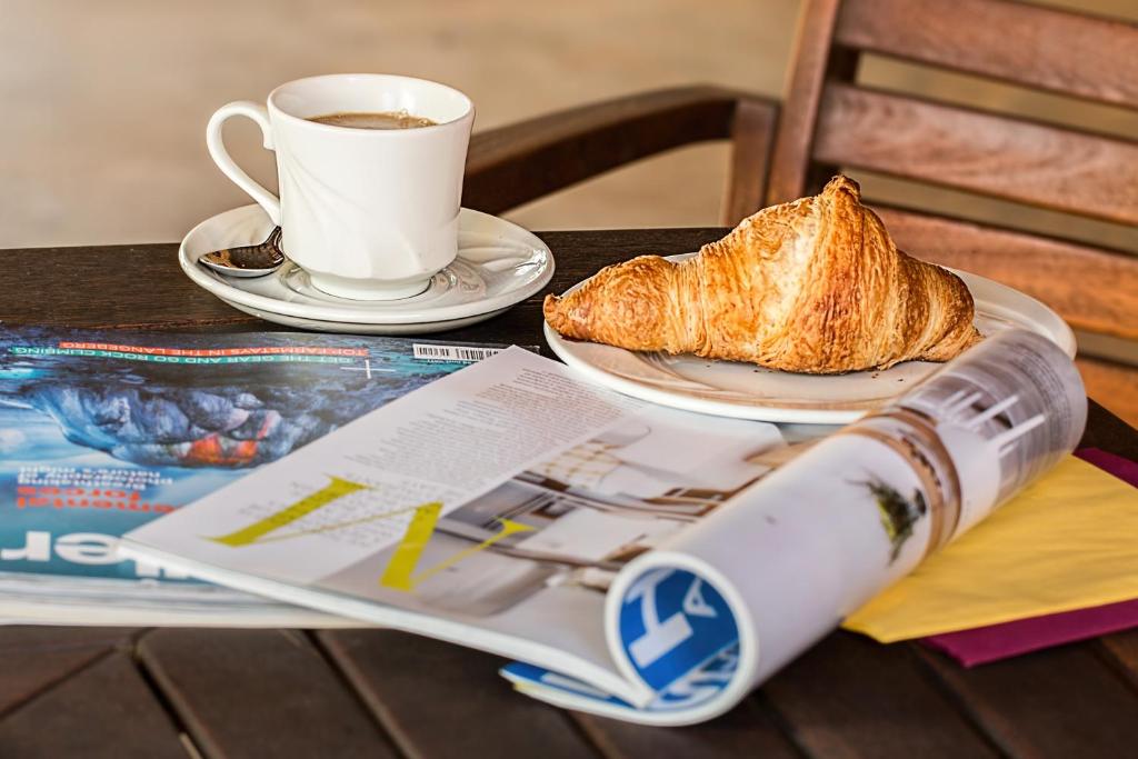 a cup of coffee and a piece of bread and a newspaper at TLC Exmouth Bed and Breakfast in Exmouth