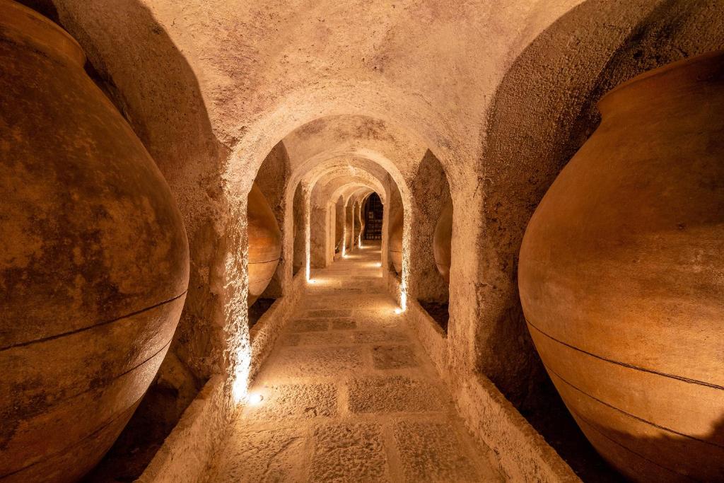 un callejón en un edificio de piedra con vasijas grandes en La Bodega de Quintín, en Villarejo de Salvanés