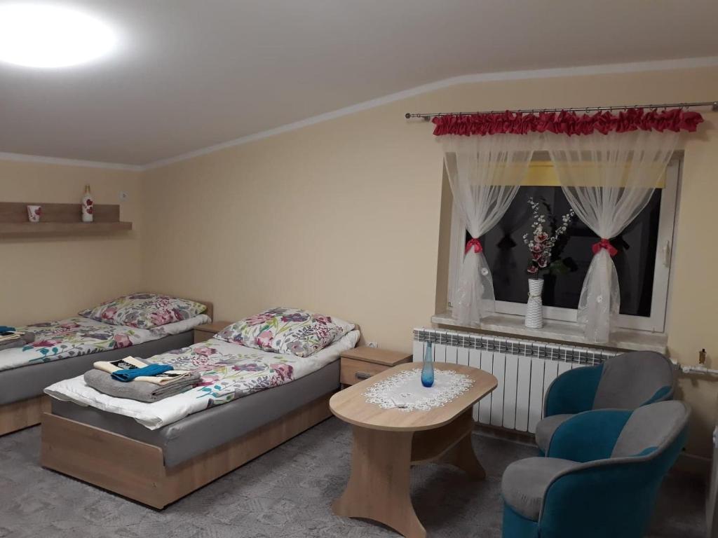 Cette chambre comprend deux lits, une table et une chaise. dans l'établissement Agroturystyka Stokrotka, à Kroczyce