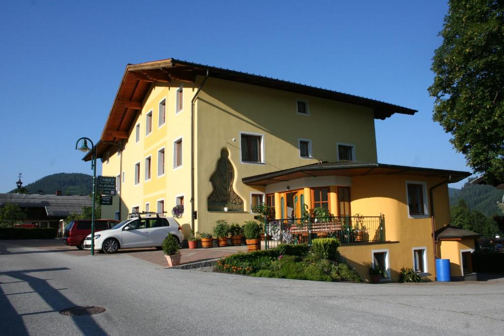 a large yellow building with a car parked next to it at Hotel Pension Barbara in Sankt Martin am Tennengebirge