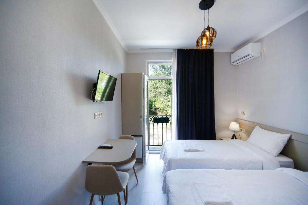 a hotel room with two beds and a table and a window at Hotel Sani Kutaisi in Kutaisi