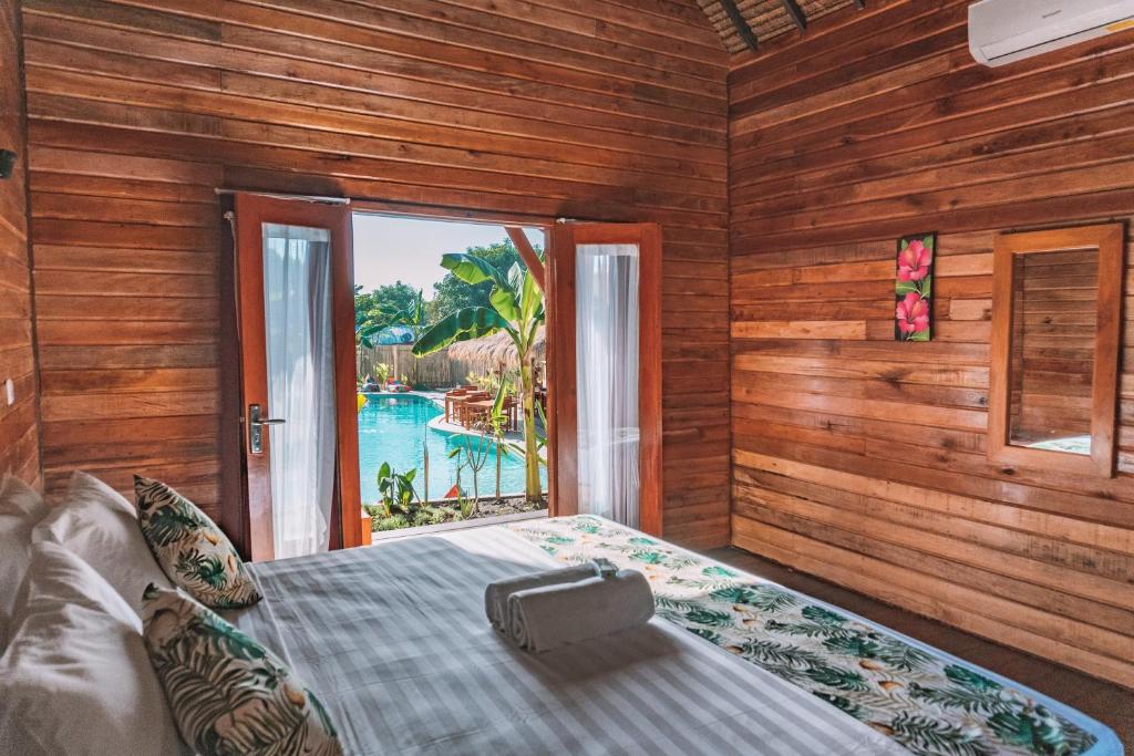 a bedroom with a bed with a view of a pool at Voodoo Gili in Gili Trawangan