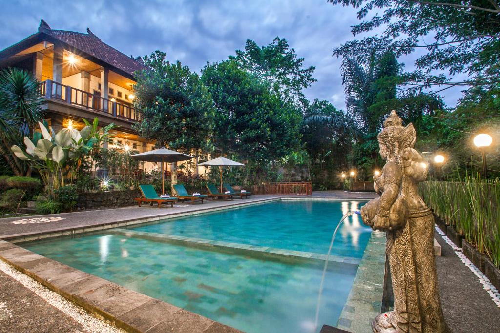 a swimming pool with a statue next to a house at Adi Jaya Cottages Ubud Suites by EPS - CHSE Certified in Ubud