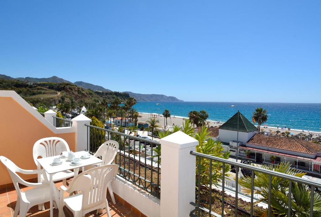 a balcony with a table and chairs and the ocean at Apartamentos HC Burriana Playa in Nerja