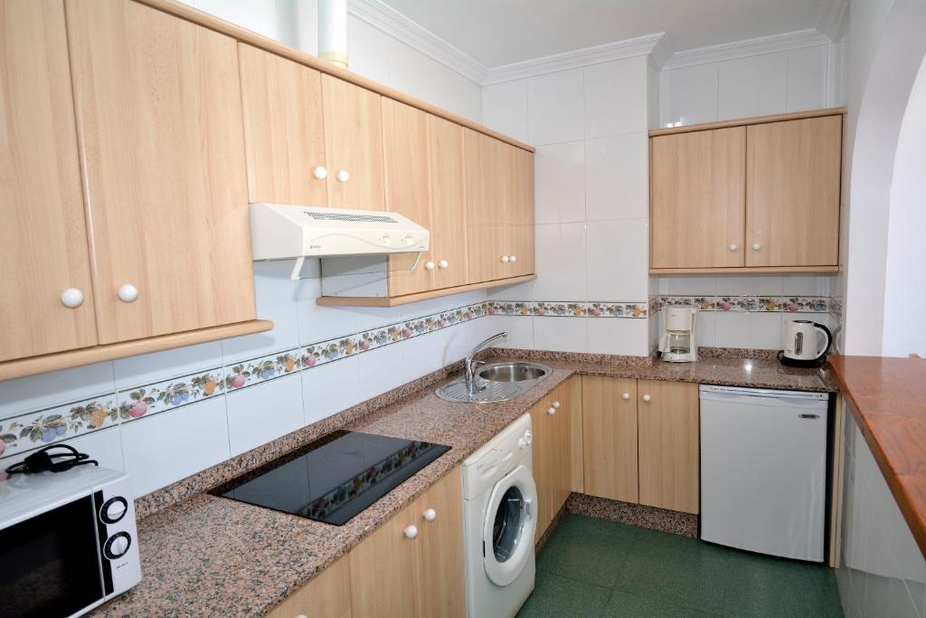 a kitchen with wooden cabinets and a washer and dryer at Apartamentos HC Burriana Playa in Nerja