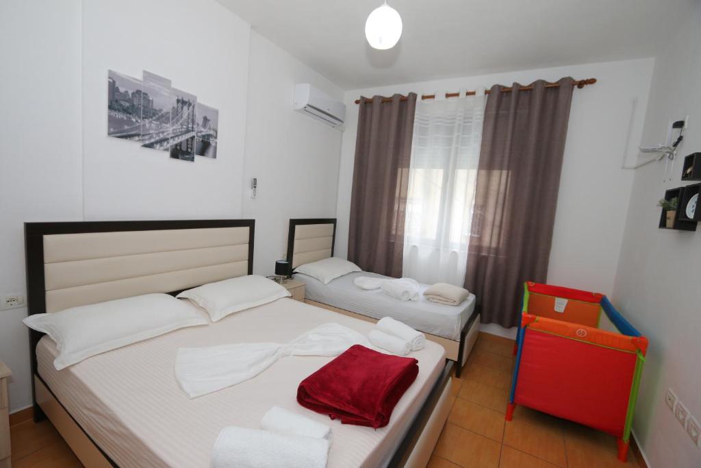 um quarto com 2 camas e uma cadeira vermelha em Sweet Living Apartment em Shkodër