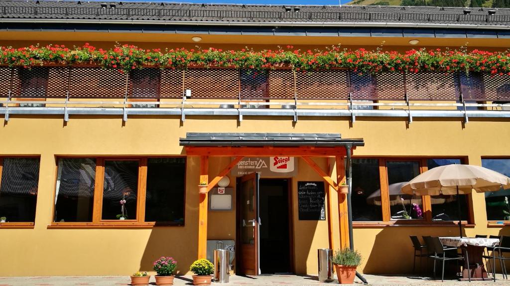 a yellow building with a balcony with flowers on it at Alpenstern Hotel in Vordernberg