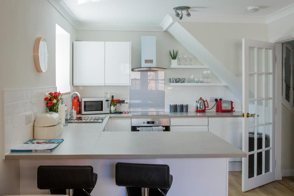 a white kitchen with a counter and chairs in it at The Haven in Dunbar