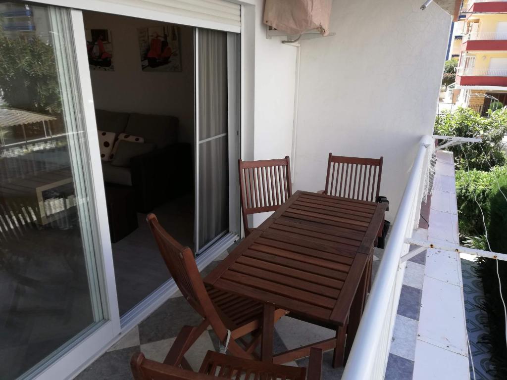 d'une table en bois et de deux chaises sur un balcon. dans l'établissement Estudios Solmar Solo Familias Serviplaya, à Gandía