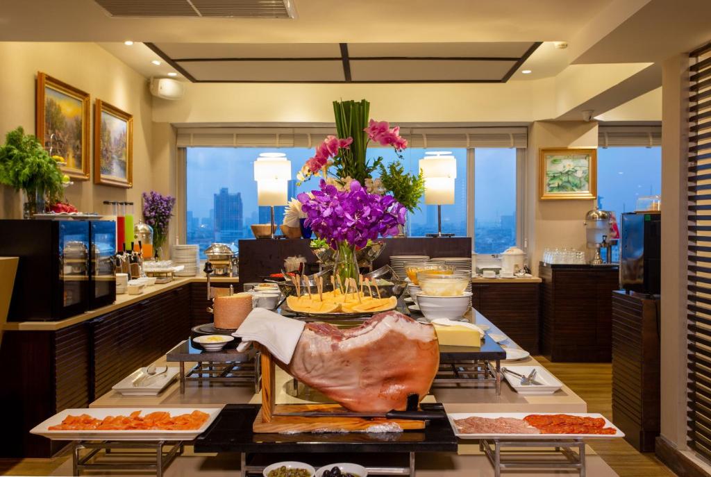 A buffet dining room with prepared dishes, a central carved roast display, and city views.