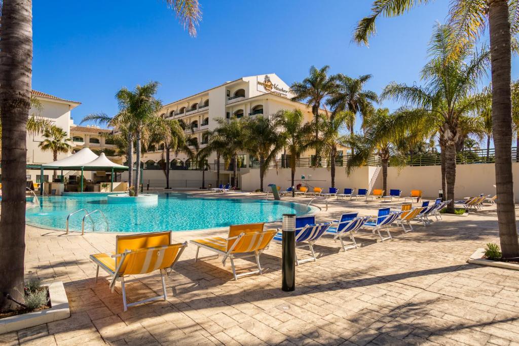 a pool at the resort with chairs and palm trees at Mirachoro Carvoeiro in Carvoeiro