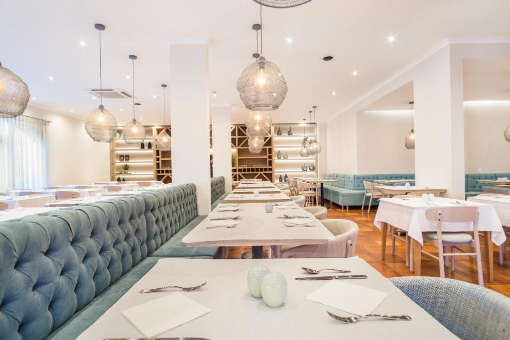 a restaurant with white tables and blue booths at Mirachoro Carvoeiro in Carvoeiro