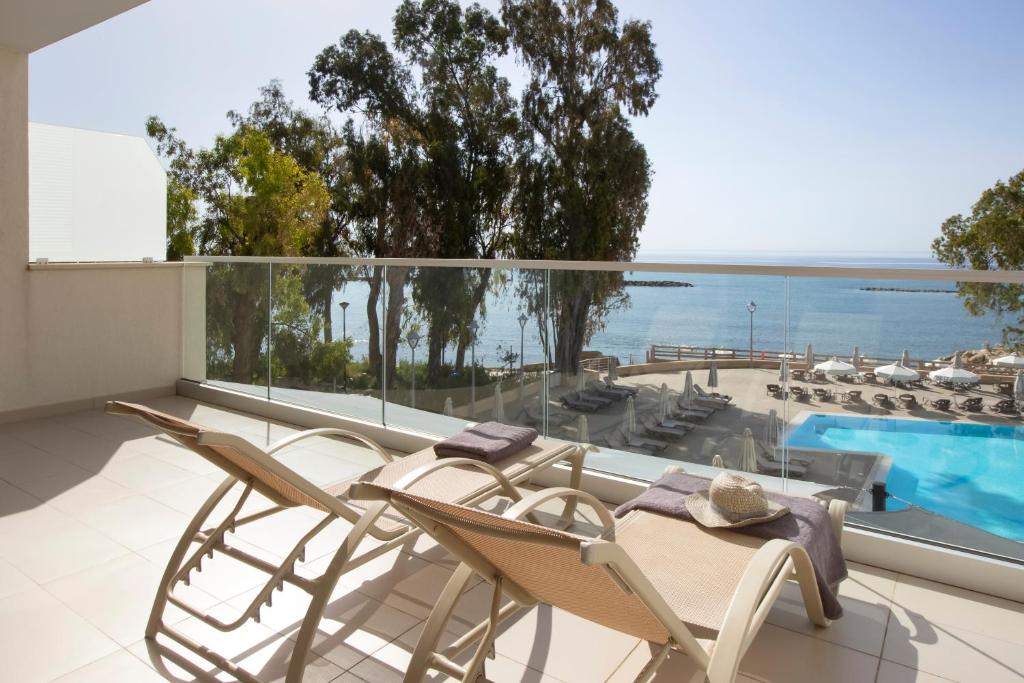 a balcony with a table and chairs and a swimming pool at Harmony Bay Hotel in Limassol