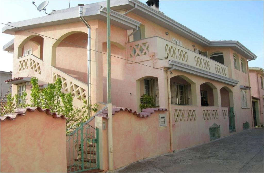 een roze gebouw met een balkon in een straat bij SANTU LUISU iun P2230 in Galtellì