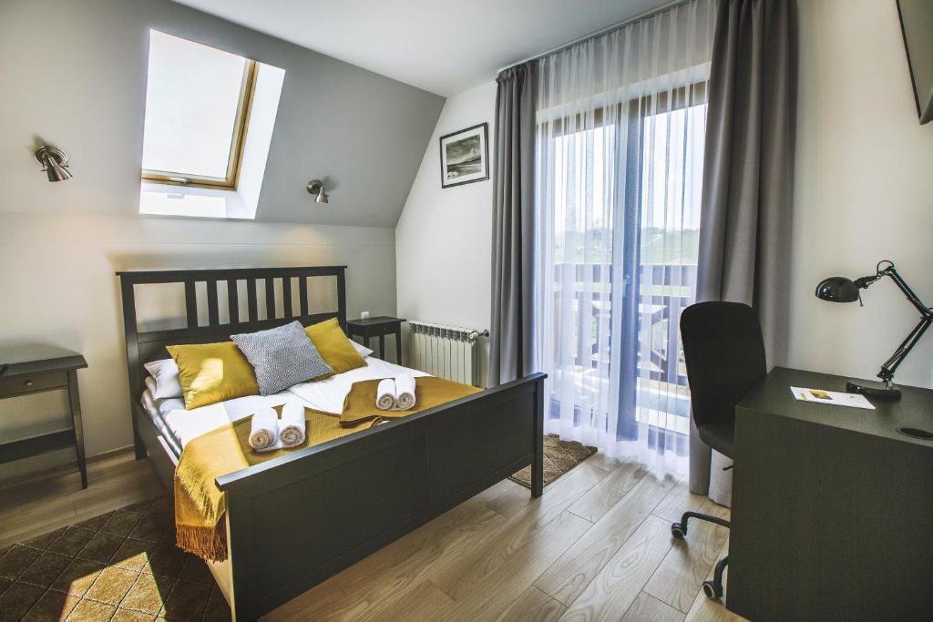 a bedroom with a bed and a desk and a window at Apartamenty GÓRKA in Białka Tatrzanska