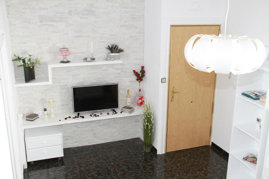 sala de estar con TV en una pared de ladrillo blanco en Shiny Per Family Apartment, en Málaga