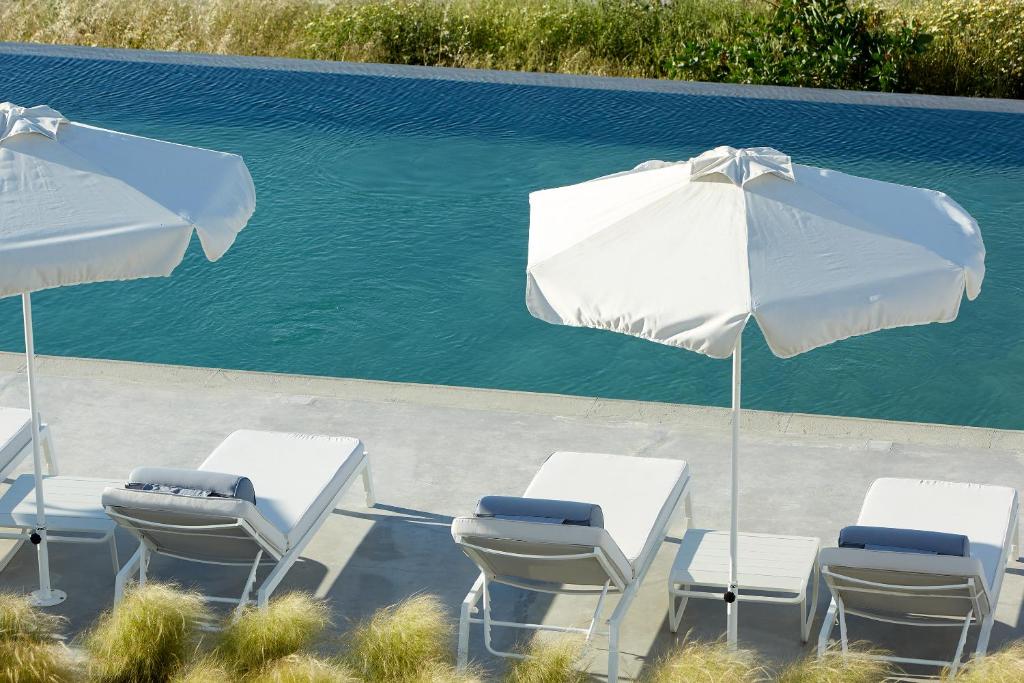 a group of chairs and an umbrella next to a pool at Milos Breeze Boutique Hotel in Pollonia