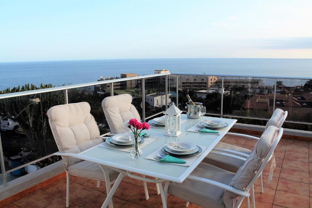 - une table blanche avec des chaises blanches et des fleurs sur le balcon dans l'établissement El Mirador de Tabaiba, à Tabaiba