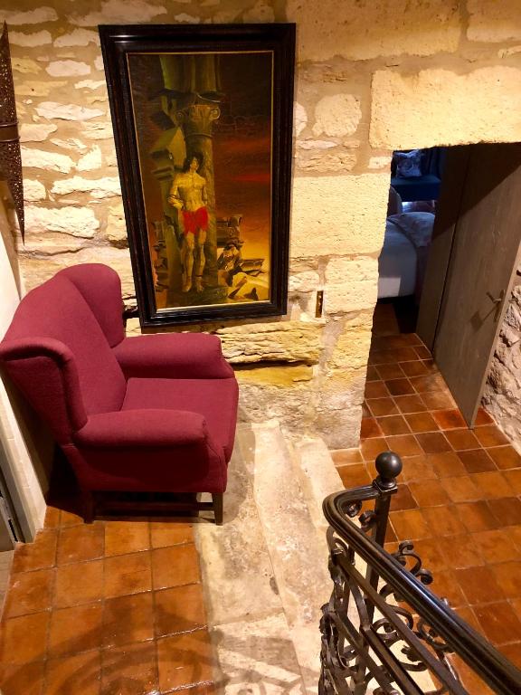 a living room with a red chair and a painting at La Maison d&#39;Alice in Vézac