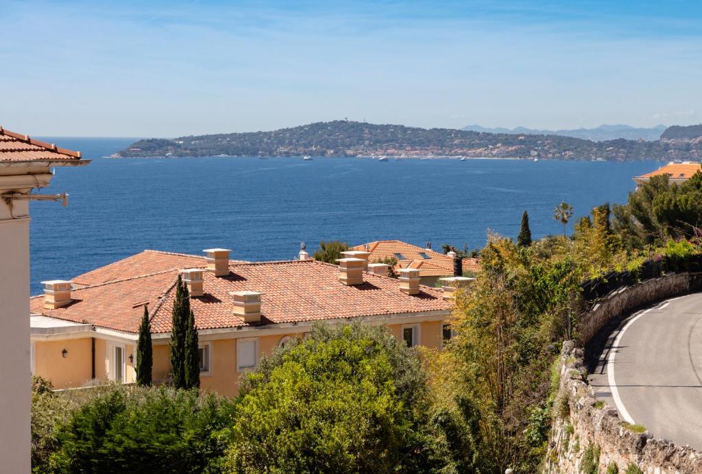 a building on the side of a hill next to the water at Hotel Miramar in Cap d'Ail