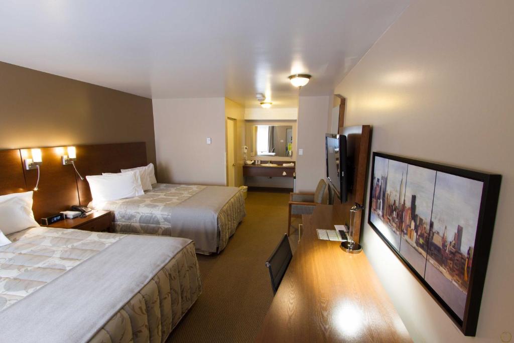 a hotel room with two beds and a flat screen tv at Motel Invitation in Sainte-Marie