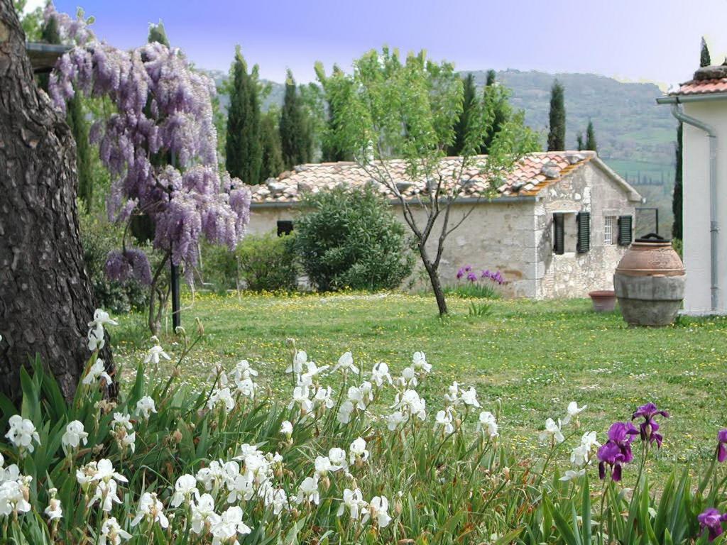 a garden with white and purple flowers and a house at Vignagrande Agriturismo in Saturnia